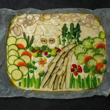Flower foccacia Cooking Focaccia. Çiğ Focaccia, parşömen kağıdındaki sebzelerle yaratıcı bir şekilde dekore edilmiş. Ekşi hamur