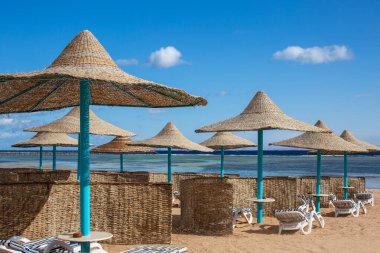 Deniz kıyısında güzel bir sahil. Wicker plaj şemsiyeleri ve rüzgar çitleri. Plaj tatilinin kavramsal görüntüsü. Boş sahil