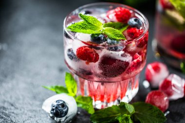 Limonatayı şekersiz, böğürtlenli, böğürtlenli ve buzlu, koyu arkaplanda ferahlatıyor. Yaz kavramsal içeceği.