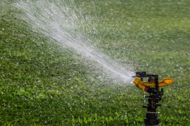Yeşil çimenlerin üzerine otomatik su fıskiyesi. Dönen kafa.