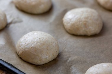 Tam tahıllı hamburger ekmeği. Pişirmeden önce hamuru düzeltiyorum. Hazırlık