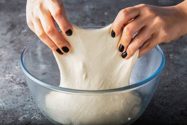 Kneading the dough using the stretch and fold method.  Sourdough wheat dough . Gluten development