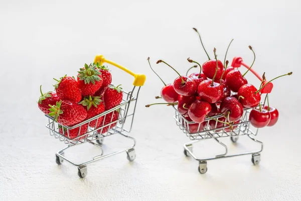 ショッピングカートで赤い熟したチェリーとイチゴ 甘いチェリーとイチゴ 毎日の料金 — ストック写真