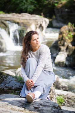 Güzel bir Bayan dikey çekim önünde bir şelale oturdu