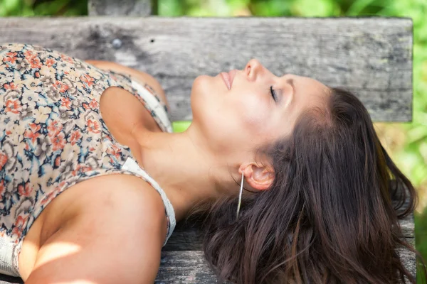 Bir bankta açık havada uykuda yalan güzel esmer Bayan.