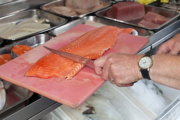 Taze somon balık için bir parça kesme bıçağı tutan bir el 
