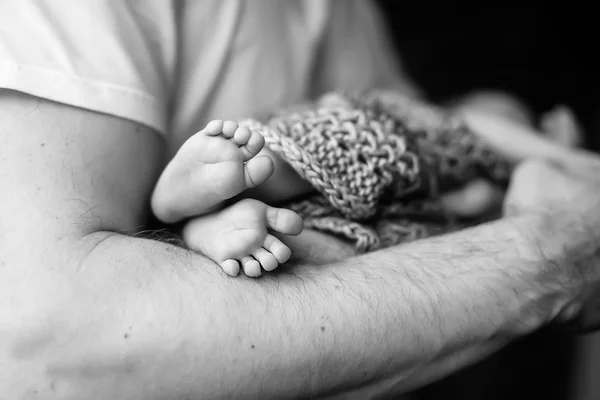 De voeten van de baby in handen van de vader. Zwart-wit foto. Baby's voeten in — Stockfoto