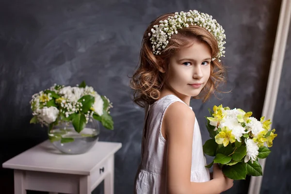 Das schöne kleine Mädchen posiert mit einem Blumenstrauß in einem — Stockfoto