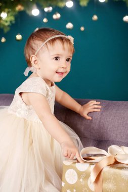 Noel ve Yeni Yıl kutlaması konsepti. Beyaz elbiseli güzel bir kız Noel ağacı ve ışıklarla oynayıp mutlu oluyor. Kış tatili.