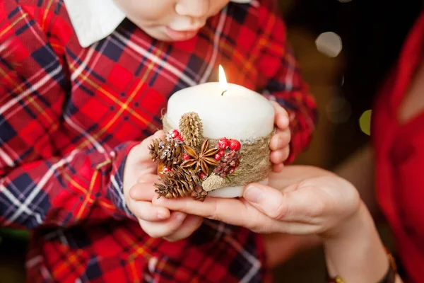 Burning candle in the hands of mother and little girl.  Christmas decor. Mom and child holding beautiful candle with fire. Christmas time. Happy family. New Year and Winter holidays