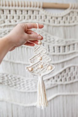 Christmas macrame decor. Female hand holding Christmas tree making in style of macrame. Boho decor, eco decorations, ornaments, hand made, wall handing,  New Year, macrame training