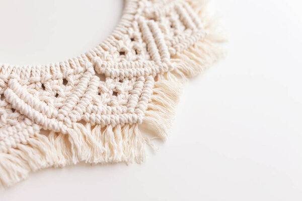 Macrame wreath on a white background close up. Natural cotton thread. Eco home decor. Copy space