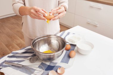 Yumurtaları kaseye kıran kadın. Metal bir kasenin üzerinde yumurta tutan eller. 