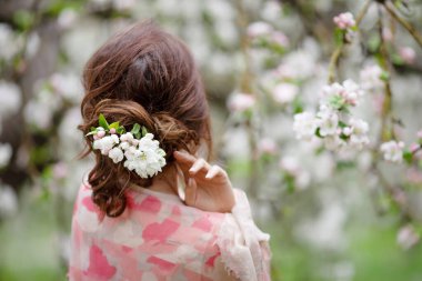 İlkbaharda çiçek açan elma bahçesinde güzel, gülümseyen esmer genç kadınlar. Doğanın tadını çıkar. Sağlıklı bir kız. Bahar konsepti Meyve bahçesindeki güzel kızın arka manzarası