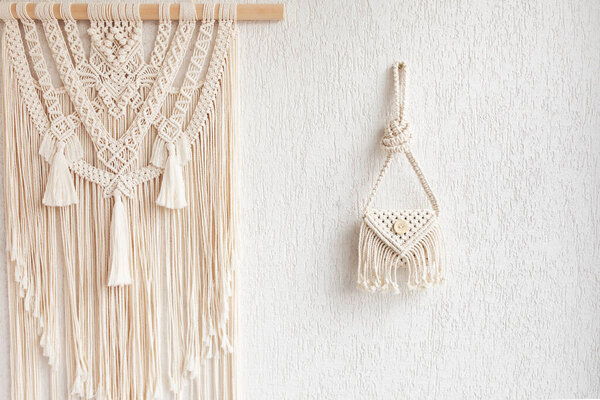 Handmade white macrame bag on the white wall, ECO friendly. Hobby knitting handmade macrame. Modern summer concept. Copy space