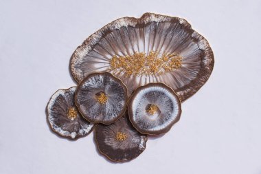 Bardak tutacağı, epoksi reçine tepsisi, gri arka planda deniz tarzı taş kesimi. Kahverengi ve gri boya lekeleri, altın kaplama. Masa ayarı için konu. Parlatıcı, yansıtıcı. Epoksi reçine altlığı. Ev dekoru