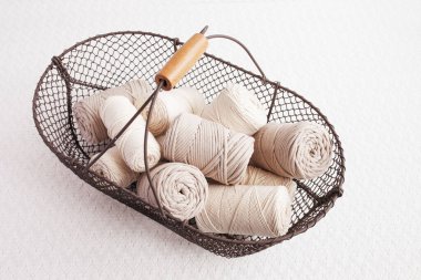 Beyaz arka planda el yapımı makrome örgü ve pamuk iplikler. Pamuk makrome kablolar ve ipler tel sepetine karşı. Makrome ve el sanatları afişleri ve reklam için iyi bir görüntü. Kapatın. Boşluğu kopyala