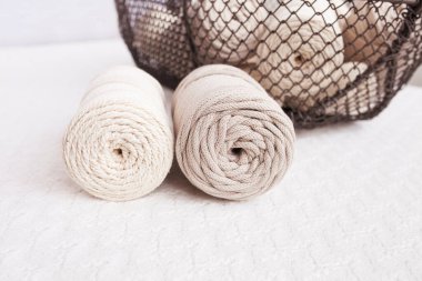 Beyaz arka planda el yapımı makrome örgü ve pamuk iplikler. Pamuk makrome kablolar ve ipler tel sepetine karşı. Makrome ve el sanatları afişleri ve reklam için iyi bir görüntü. Kapatın. Boşluğu kopyala