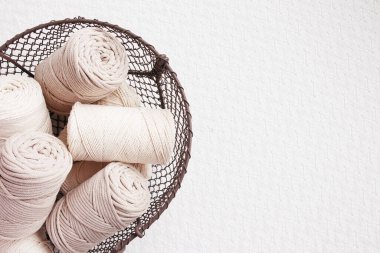 Beyaz arka planda el yapımı makrome örgü ve pamuk iplikler. Pamuk makrome kablolar ve tel sepetteki ipler. Makrome ve el sanatları afişleri ve reklam için iyi bir görüntü. Kapatın. Boşluğu kopyala