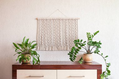 El yapımı makrome. Beyaz bir duvara asılı ahşap sopayla% 100 pamuk duvar süslemesi. Makrame örgü ve pamuk iplikleri. Kadın hobisi. ECO dostu modern örgü DIY doğal dekorasyon konsepti iç mekanda