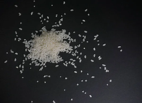 Riz blanc non cuit éparpillé dans les céréales sur fond noir — Photo