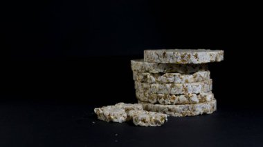 Tahıllı gevrek, çıtır pilav ve diyet ekmek. Bir yığın patlamış tahıllı çıtır ekmek. Pirinç keki siyah arkaplanda pirinç kabartması.