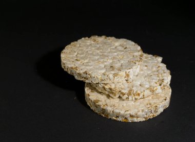Tahıllı gevrek, çıtır pilav ve diyet ekmek. Bir yığın patlamış tahıllı çıtır ekmek. Pirinç keki siyah arkaplanda pirinç kabartması