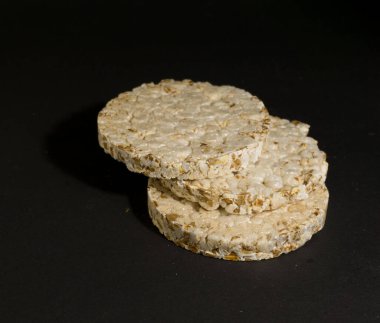 Tahıllı gevrek, çıtır pilav ve diyet ekmek. Bir yığın patlamış tahıllı çıtır ekmek. Pirinç keki siyah arkaplanda pirinç kabartması