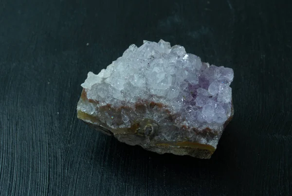 Amethyst violet variety of quartz from Brazil. Natural mineral stone on black background. Mineralogy, geology, magic of stones, semi-precious stones and samples of minerals. Close-up macro photo.