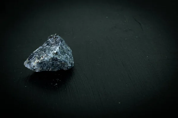 Granit. Natürlicher Mineralstein auf schwarzem Grund, umgeben von Moos. Mineralogie, Geologie, Magie, Halbedelsteine und Mineralproben. Makroaufnahme aus nächster Nähe — Stockfoto