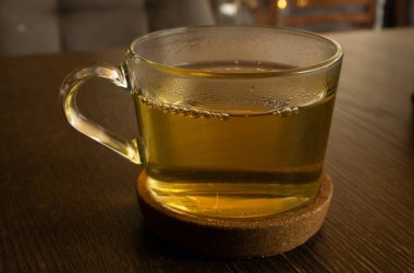 Kahverengi bir masanın mantar tezgahında şeffaf yeşil ışık çayı.