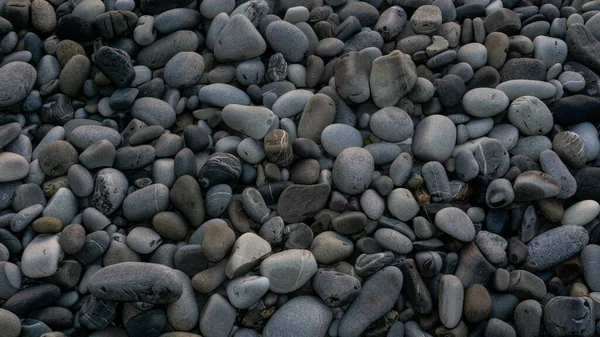 Fond en pierres de mer avec de petits cailloux ou en pierre dans le jardin ou au bord de la mer ou sur une plage. Une vue rapprochée de pierres rondes polies et lisses — Photo