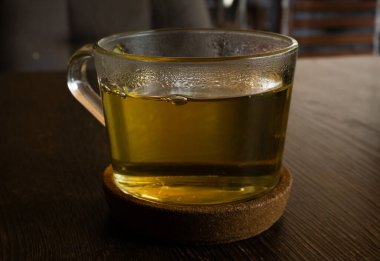 Kahverengi bir masanın mantar tezgahında şeffaf yeşil ışık çayı.