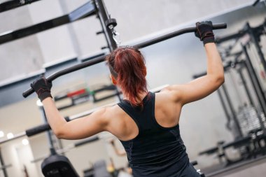 Kız atletizm antrenmanı. Sırt kasları şişiyor. Spor salonunda aşağı çekiliyor..