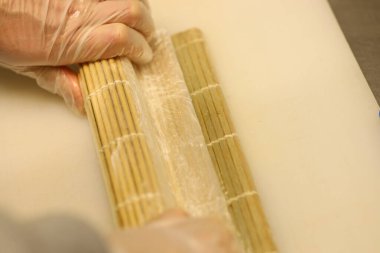 Eller mutfak ortamında bambu hasırları kullanarak suşi yuvarlıyor. Paskalya kutlaması sırasında aile ve arkadaşlar birlikte yemek hazırlar, eğlenceli anlar yaratırlar..