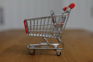 Tahta masadaki küçük metal alışveriş arabasının yanına.