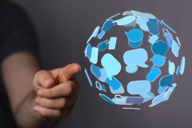 Konuşma baloncuklarından yapılmış bir küreyi işaret eden kişi, iletişim konsepti