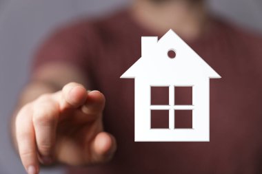 Ev modeline el işareti, emlak yatırımını temsil ediyor.