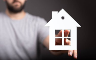 Beyaz Saray modelini elinde tutan adam emlak ve evi temsil ediyor.