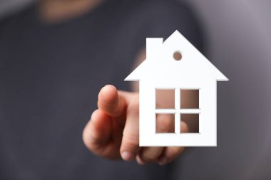 Ev sahibini ve gayrimenkulü temsil eden bir ev modelini işaret ediyor.