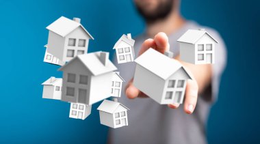 Mülkiyet kavramını ve yatırımı temsil eden minyatür beyaz evler tutan kişi