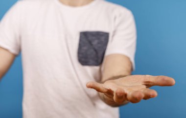 Mavi bir arkaplana karşı açık bir jest olarak boş el teklif eden adam