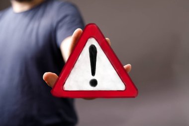 El, Kırmızı Üçgen Uyarı İşareti ile Ünlem İşaretini Sunar