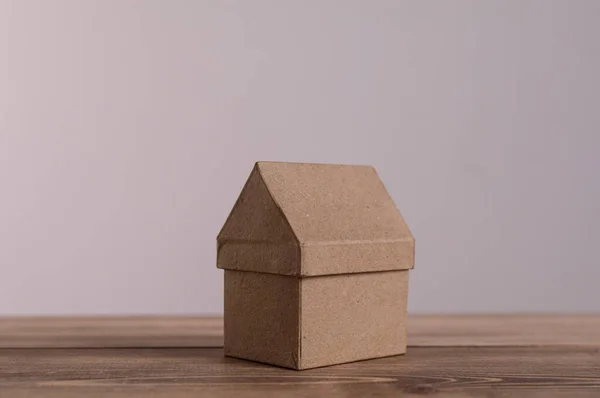 Cardboard house model on wooden surface symbolizing real estate