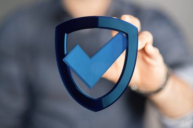 Güvenlik ve veri koruması için kontrol işaretli mavi kalkan sembolü tutan adam.