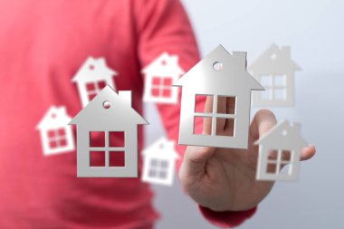 Emlak piyasasını sembolize eden 3 boyutlu evler tutan kişi