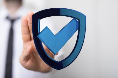 Güvenlik konsepti işaretli mavi bir kalkan tutan adam..