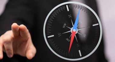 İşletme yöneticisi pusulayı işaret ediyor, karar verme kavramı.