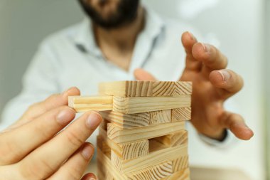 Adam dikkatli bir şekilde tahta bloğu dengeleme kulesinden kaldırıyor.