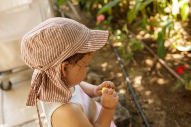 Küçük kız dışarıda oynuyor Çizgili şapkalı.